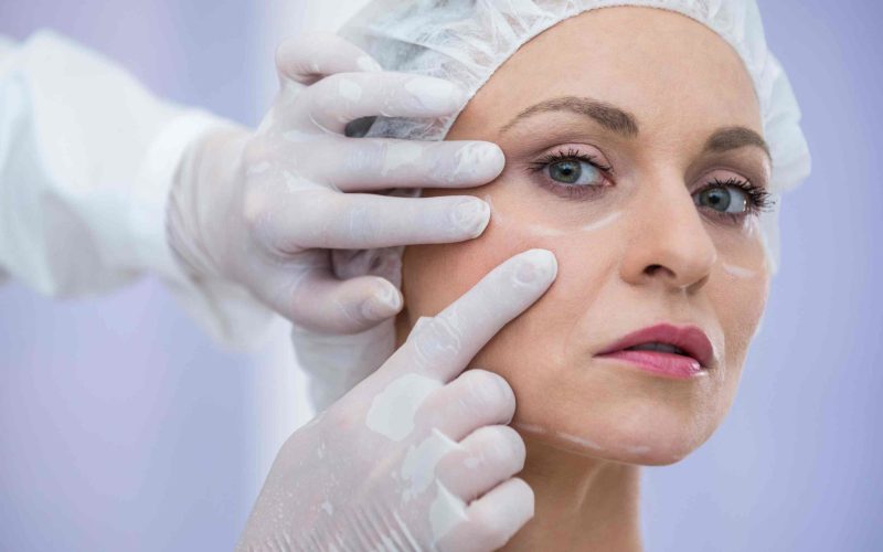 Close-up of doctor examining female patients face for cosmetic treatment